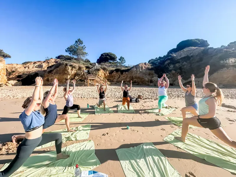 Group practicing yoga on a sunny beach in Albufeira