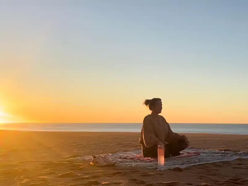 Female meditating on the beach during sunrise