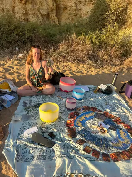 Participants holding warm cups of ceremonial cacao during a beach full moon gathering in Albufeira.