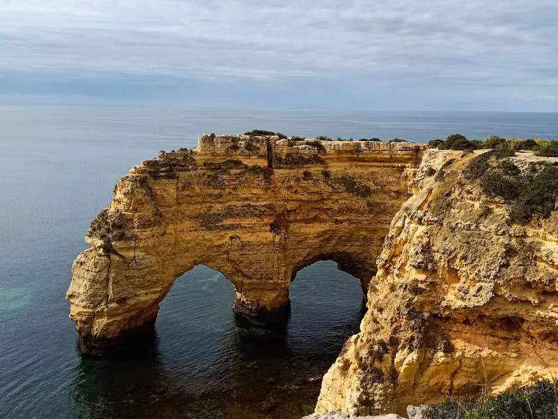 A peaceful morning scene of people practicing gentle Qigong on the beautiful cliffs overlooking the ocean at Marinha Beach at sunrise.