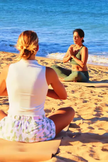 A calm morning scene of people practicing yoga on a sandy beach in Albufeira with a vibrant sunrise over the ocean in the background.