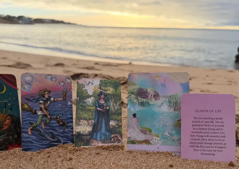 A calm and welcoming setup for a spiritual reading on a beautiful sandy beach in Albufeira, featuring tarot and oracle cards near the gentle ocean waves.