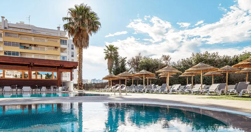 A sparkling outdoor pool and a soothing indoor jacuzzi area bathed in natural light at a peaceful wellness center in Portimão.