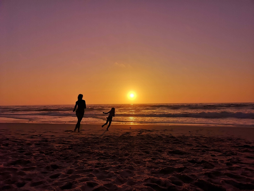 Mother and daughter playing on the beach during sunset